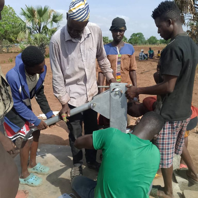Community members assembling a hand pump at a borehole