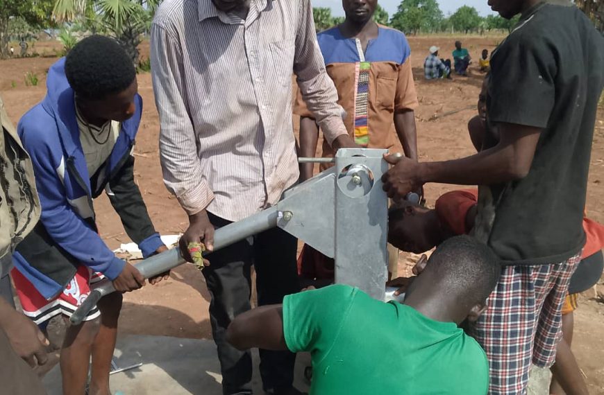 Community members assembling a hand pump at a borehole