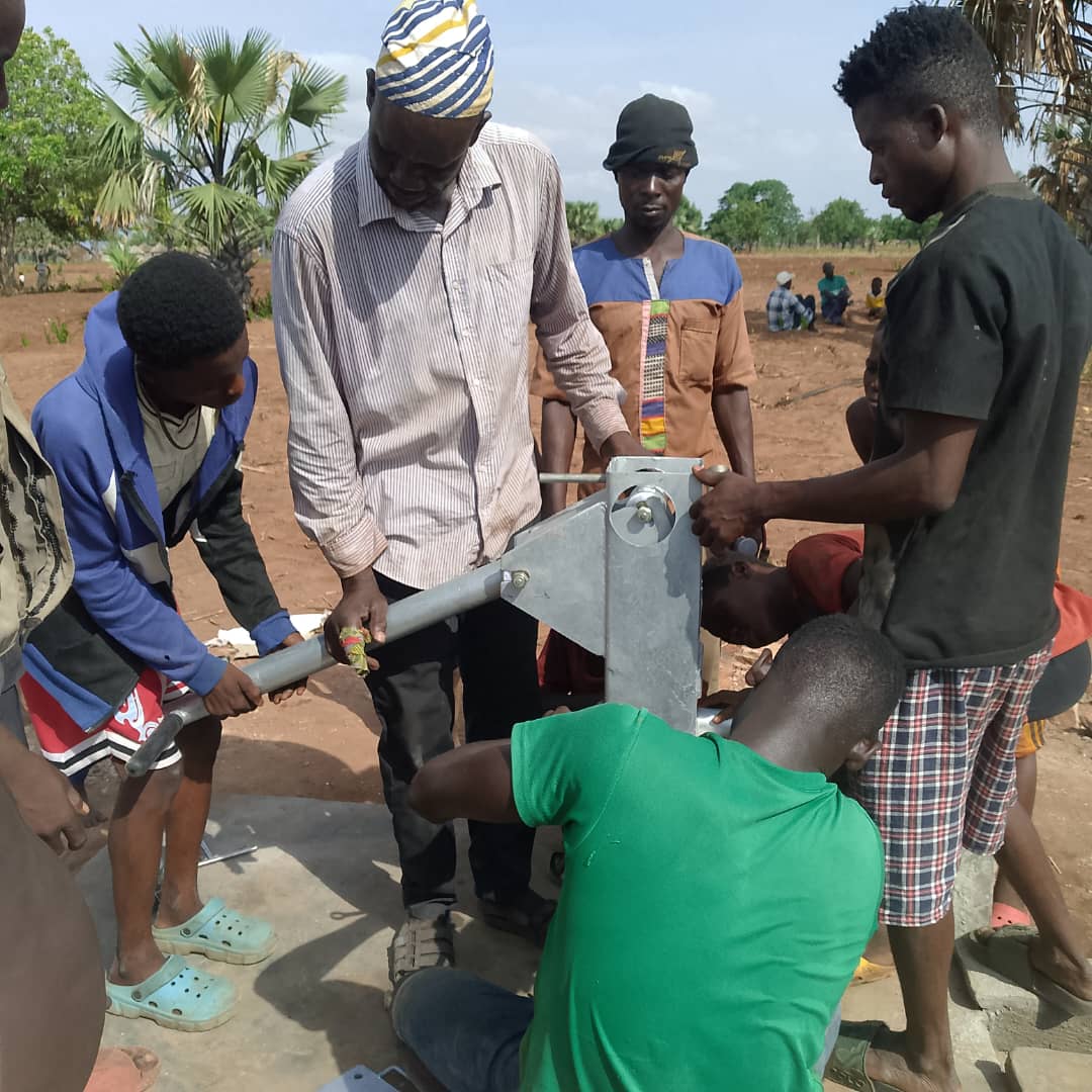 Community members assembling a hand pump at a borehole